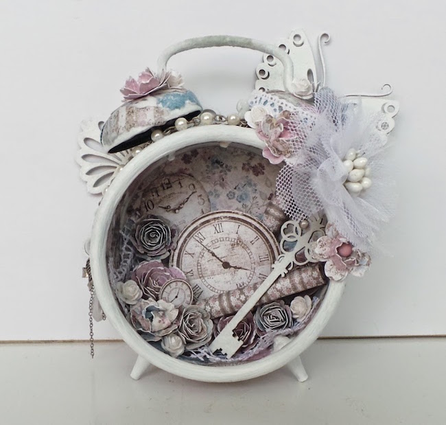 White vintage alarm clock with paper flowers and key inside