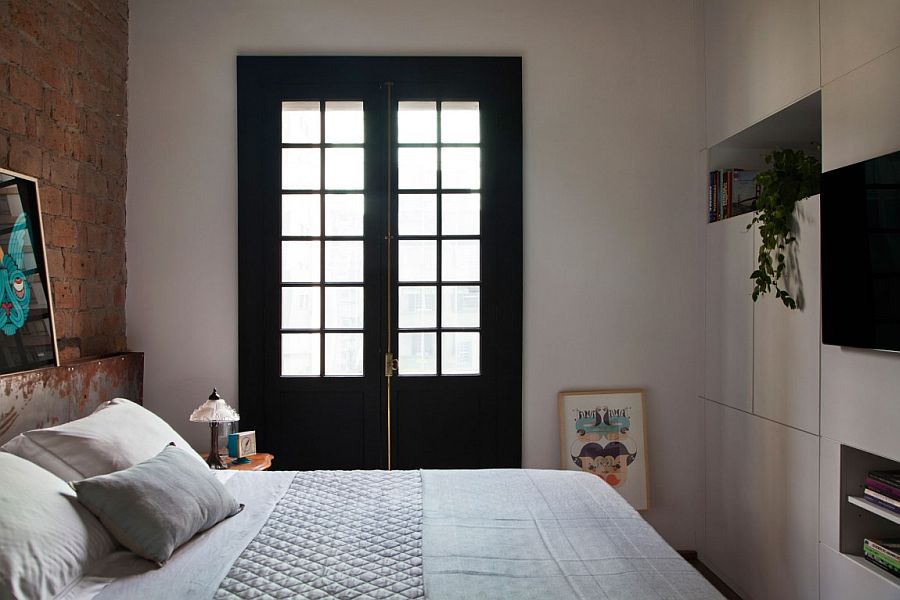 Dark window frames and exposed brick headboard wall style the small bedroom