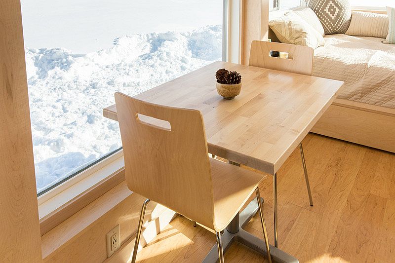Small dining table and twin chairs next to the window inside the tiny home