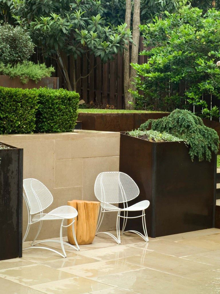 A metal planter contains overflowing plants