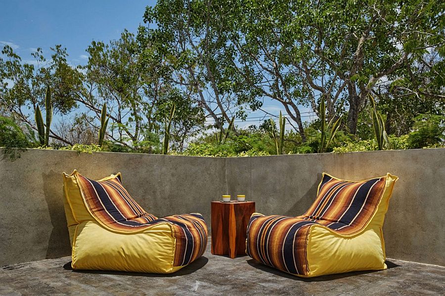 Bright yellow outdoor cushioned chairs with colorful stripes on a casual cement deck