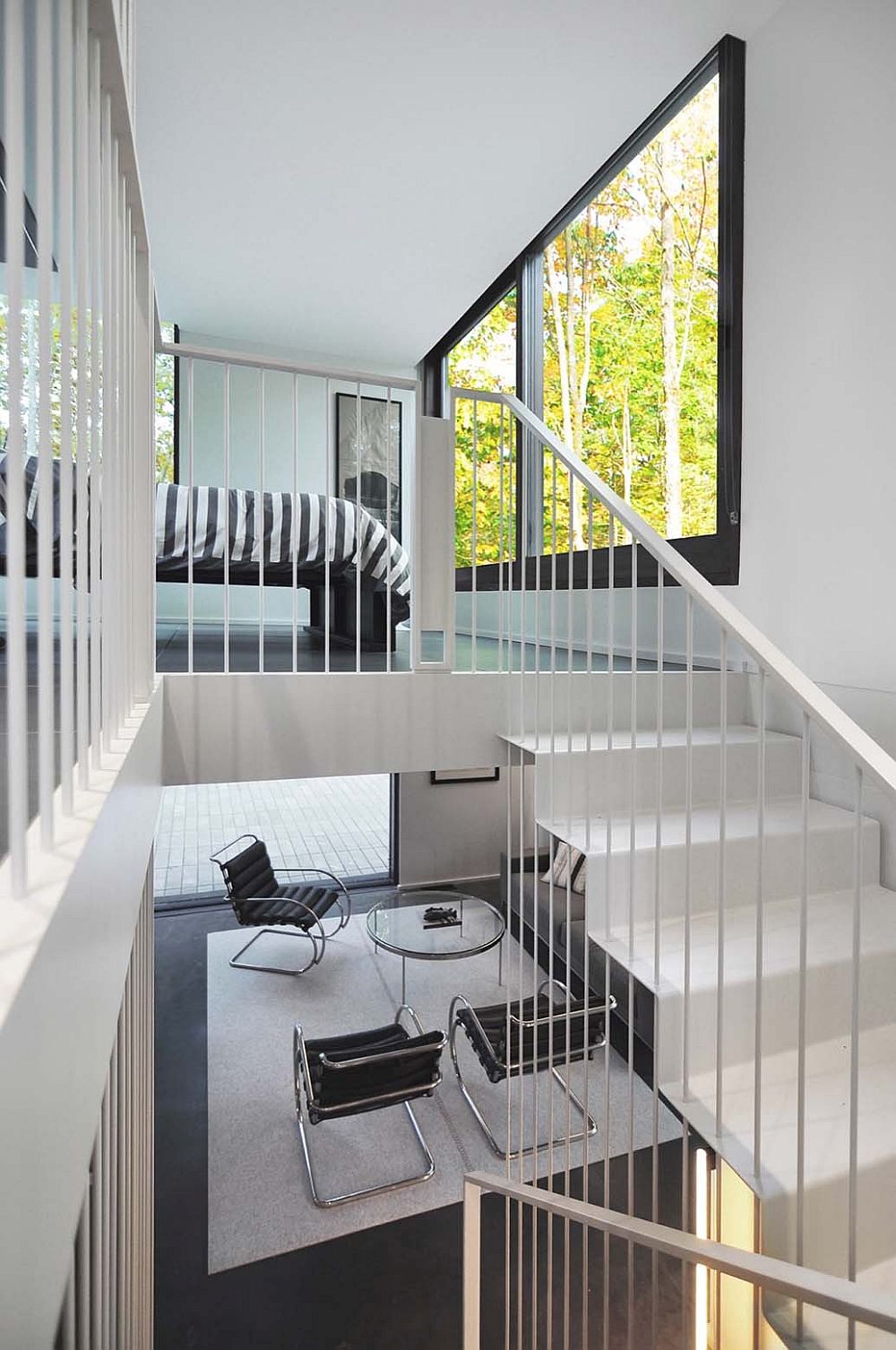 Delicate and sculptural staircase leads to the master bedroom on the top level overlooking the forest