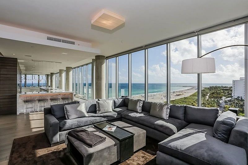 Floor-to-ceiling glass windows open up the penthouse to the beach life outside