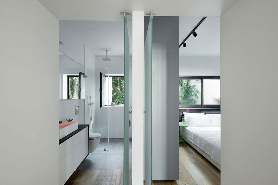 Glass walls separate the master bedroom from the bathroom