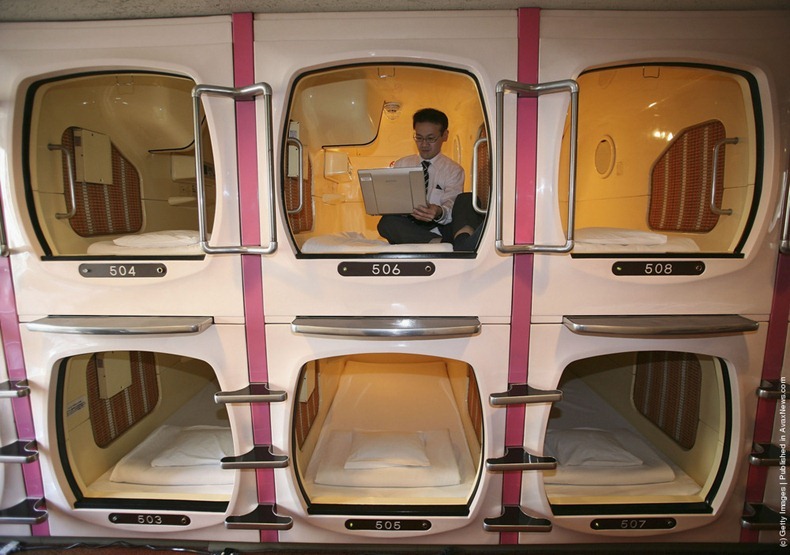 Businessman works inside sleeping pod at Japanese capsule hotel