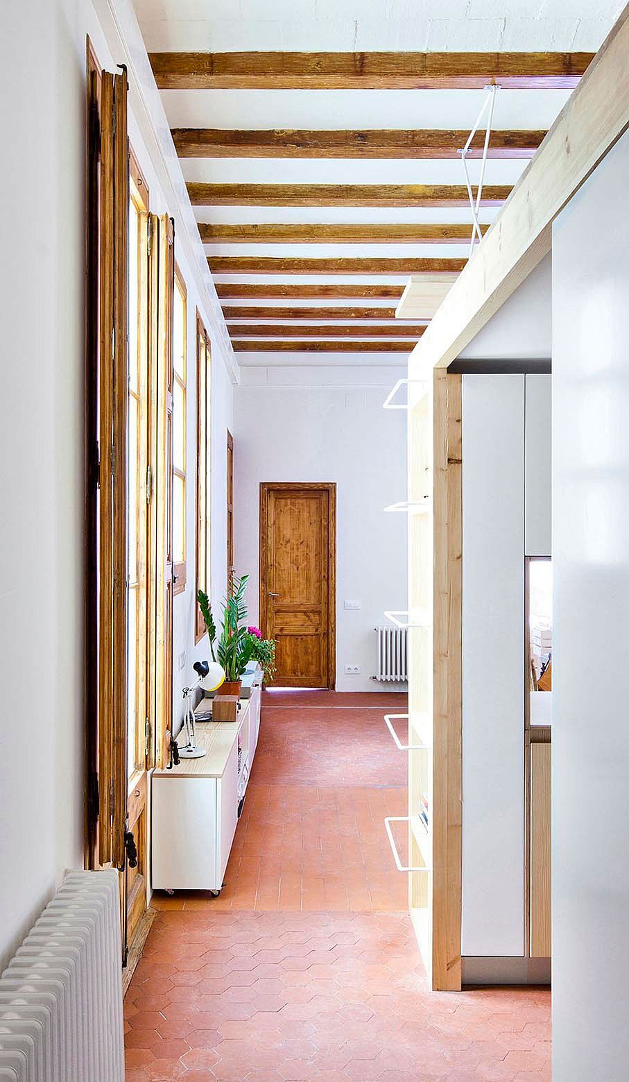 Large windows and exposed wooden beams showcase the past of the apartment