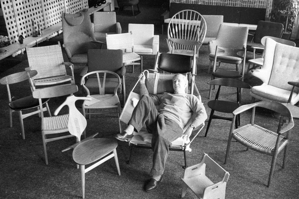 Wegner is pictured lounging on the Flag Halyard Chair, surrounded by his many chair designs. Image via The Line.