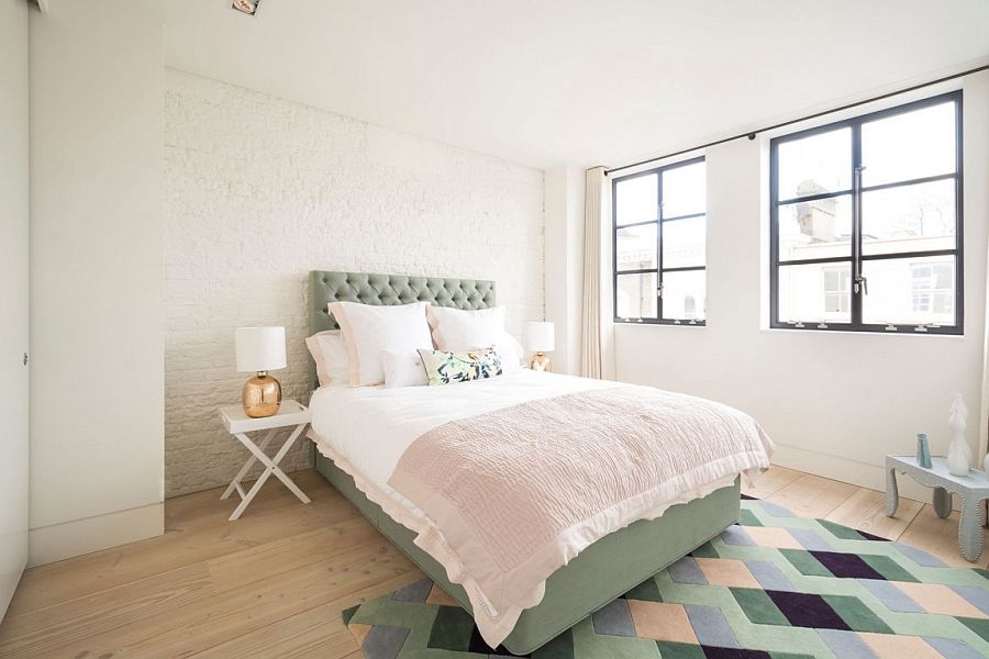 Whitewashed exposed brick wall and colorful rug with geometric pattern in the bedroom