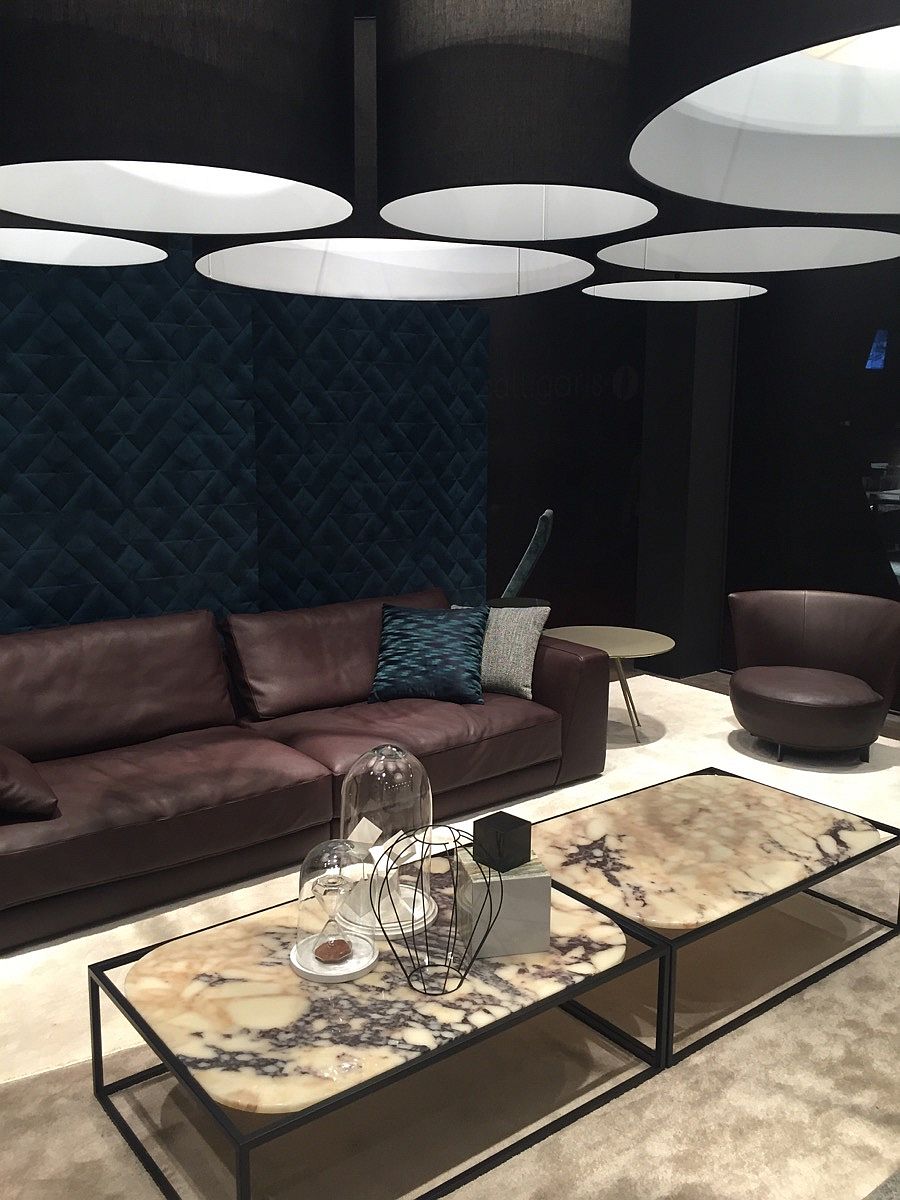 Dark leather sofas coupled with beautiful coffee tables and drum pendants