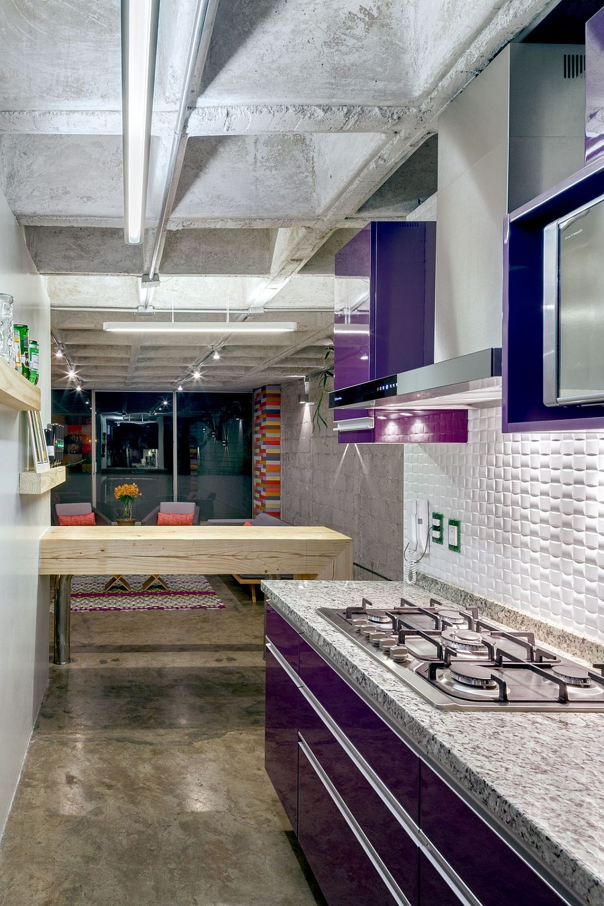 Aubergine-purple polyester cabinets and recycled timber breakfast bench inside the small kitchen