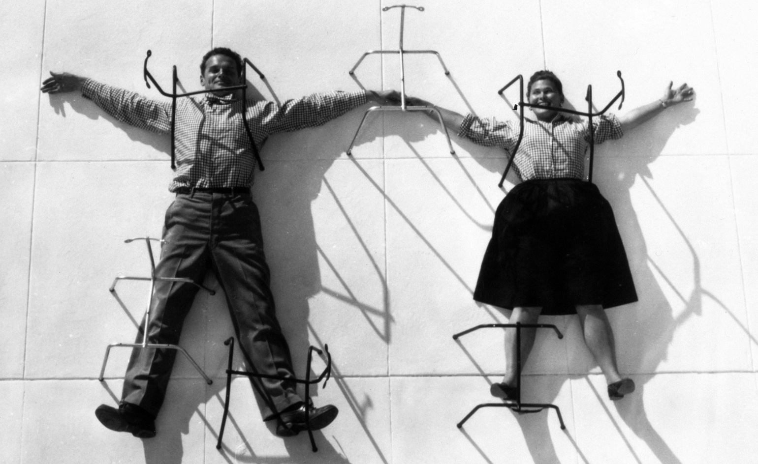 Charles and Ray Eames posing with chair bases