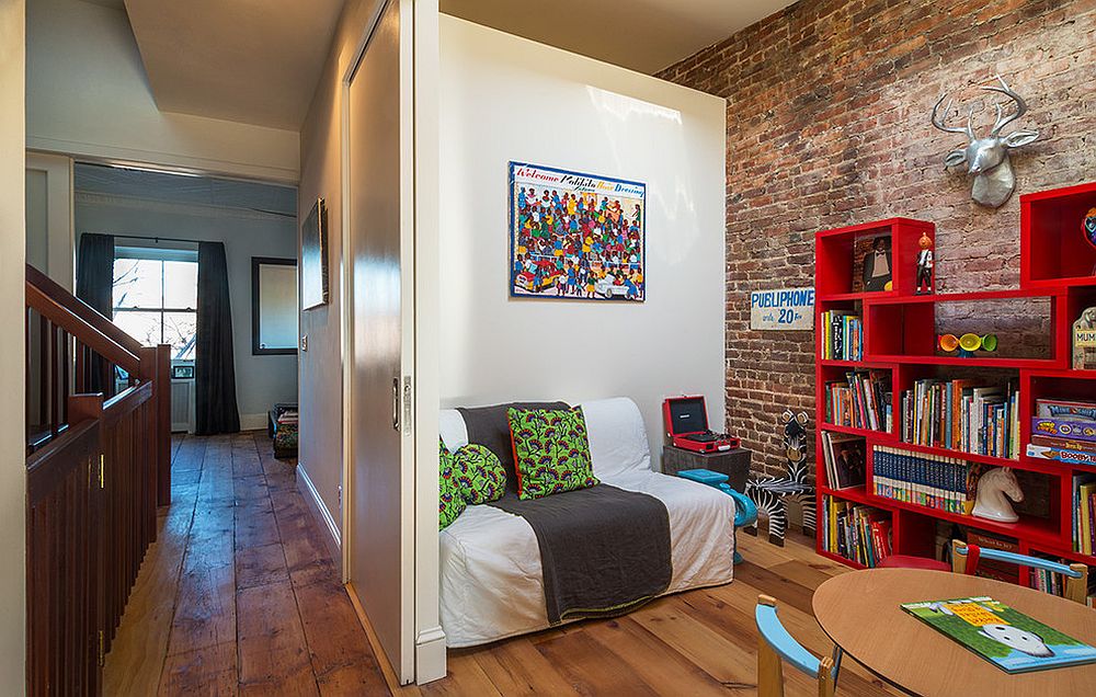 Contemporary kids' room with sofa bed and smart bookshelves in red [Design: Urban Pioneering Architecture]