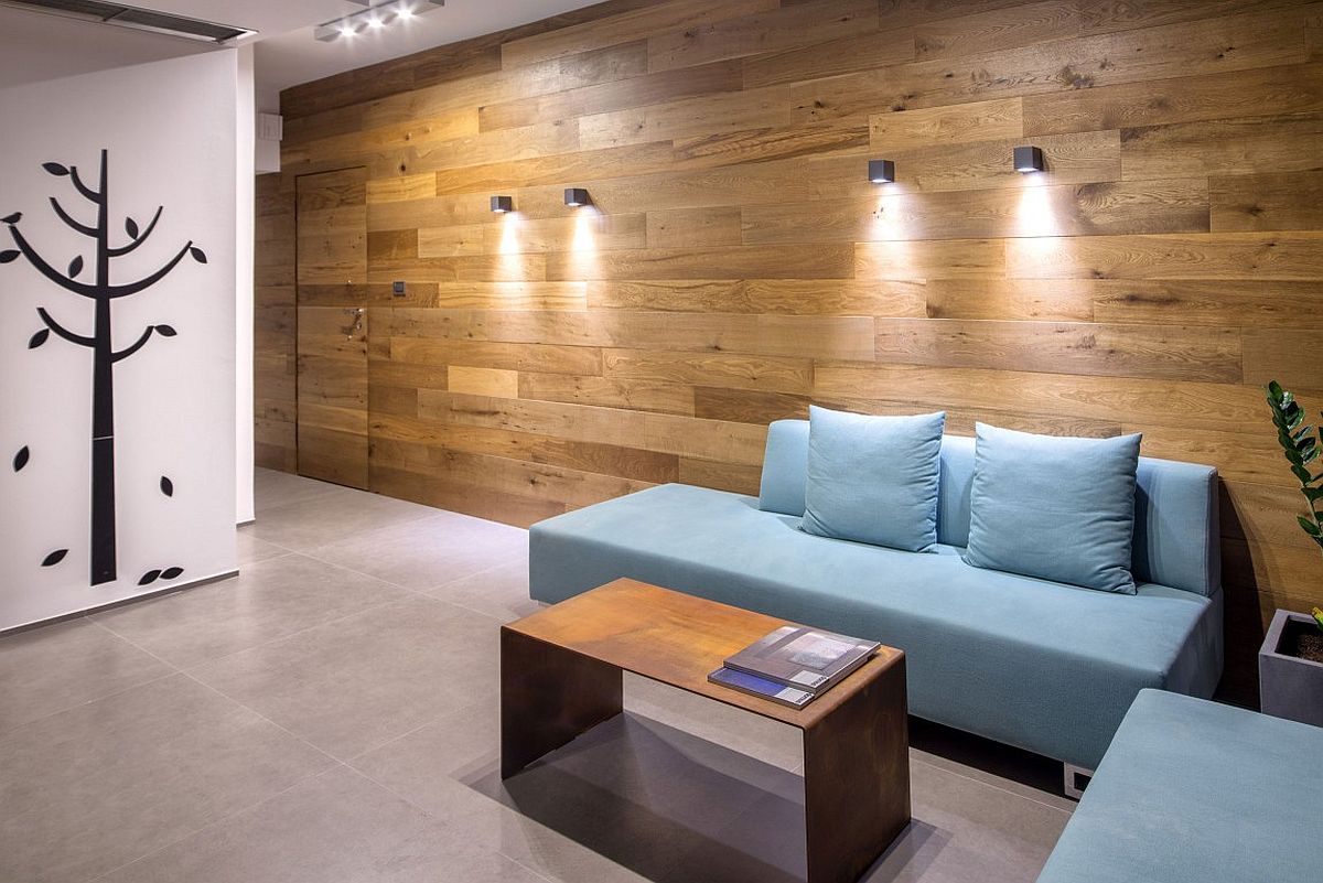 Contemporary sofas in pastel blue and wall covered in wooden panels create a smart lounge