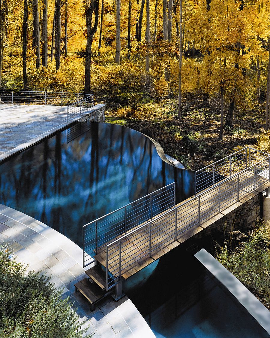 Free-form, contemporary pool with a bridge above it that leads into the woods [From: Lewis Aquatech - Julia Heine/McInturff Architects]