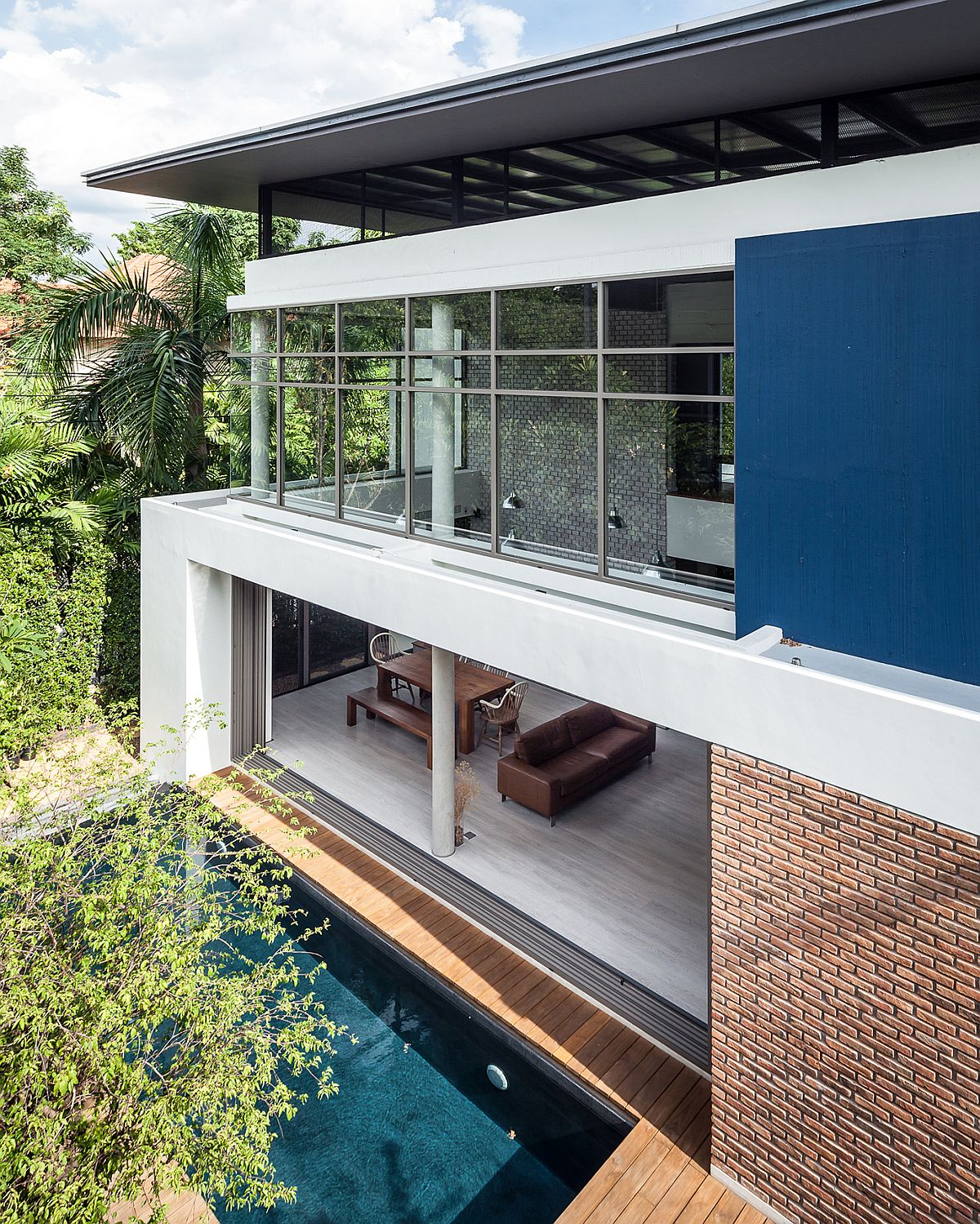 Large sliding glass doors and windows open up the Thai home towards the patio and pool area