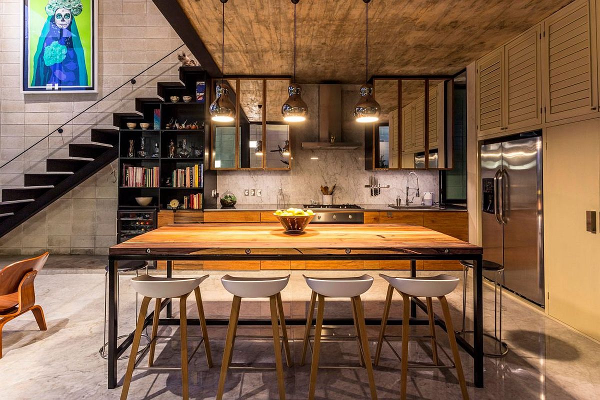 Metallic pendant lights for the dining space with a bookshelf and kitchen in the backdrop