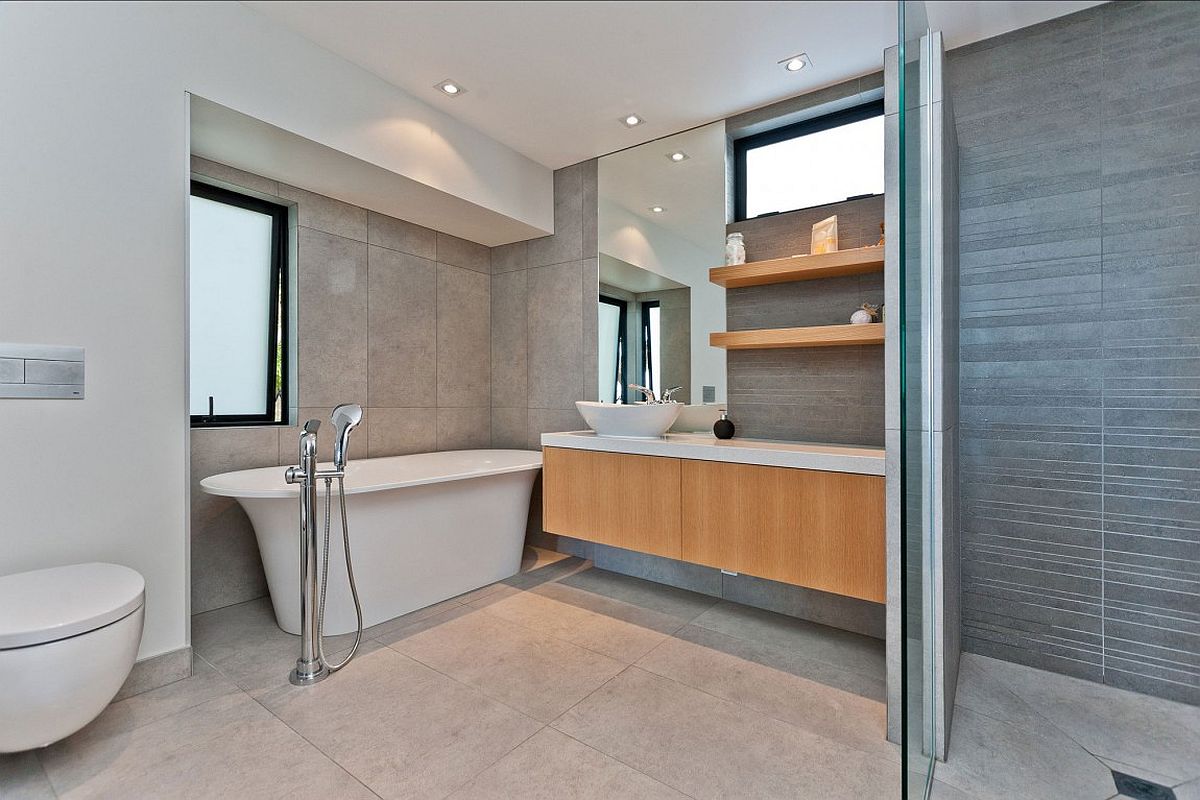 Modern bathroom with floating vanity, white bathtub and floating shelves