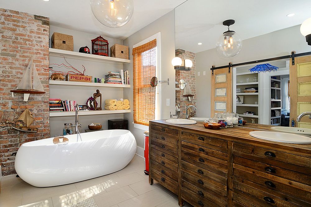 Modern eclectic bathroom with exposed brick wall, rustic wooden vanity and ample shelf space [Design: Hudson Place Realty]