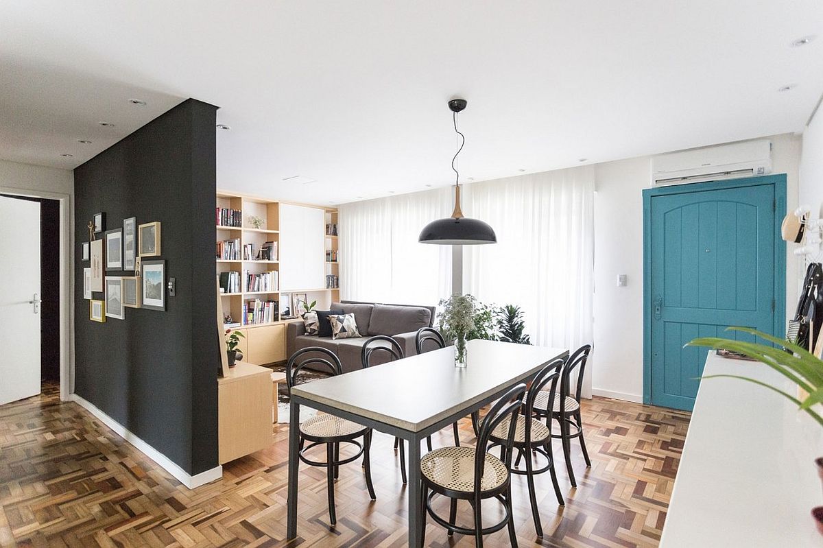 Open living area of the small Brazilian apartment with dining room and a colorful door in the backdrop