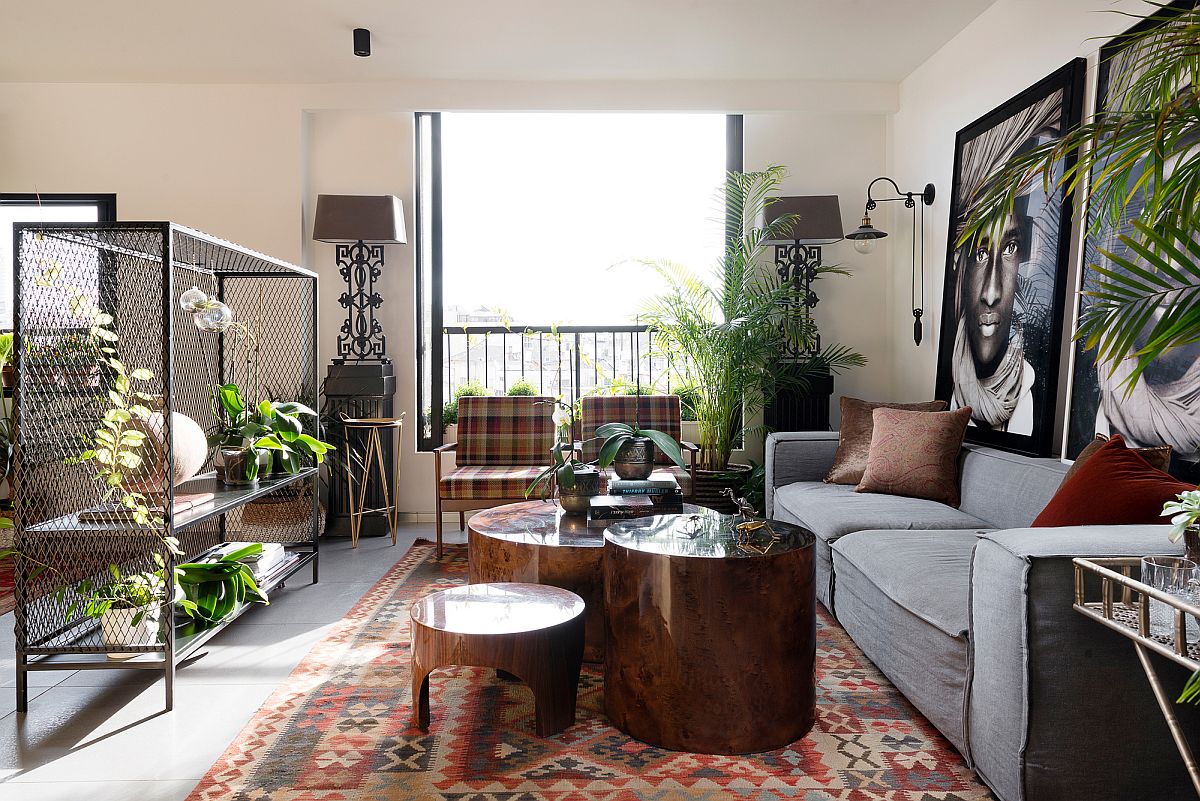 Plush gray couch, metal mesh plant holder, custom upholstered chairs and cool coffe tables shape a lovely living room