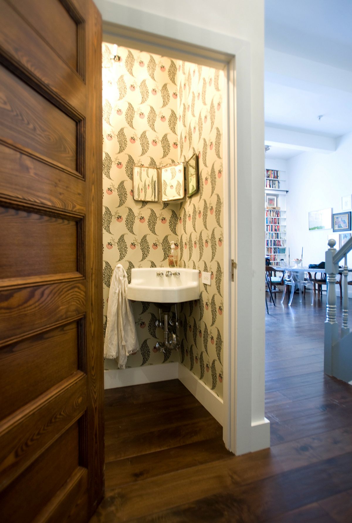 Salvaged door and vintage wallpaper revitalize the small  powder room