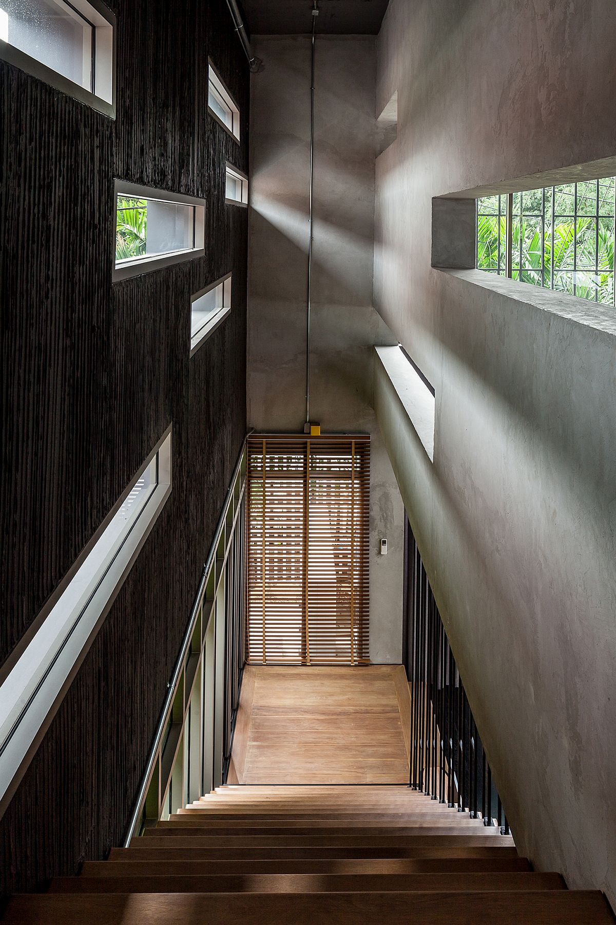 Staircase flanked by texturally two different walls fetaures little windows that bring in natural light