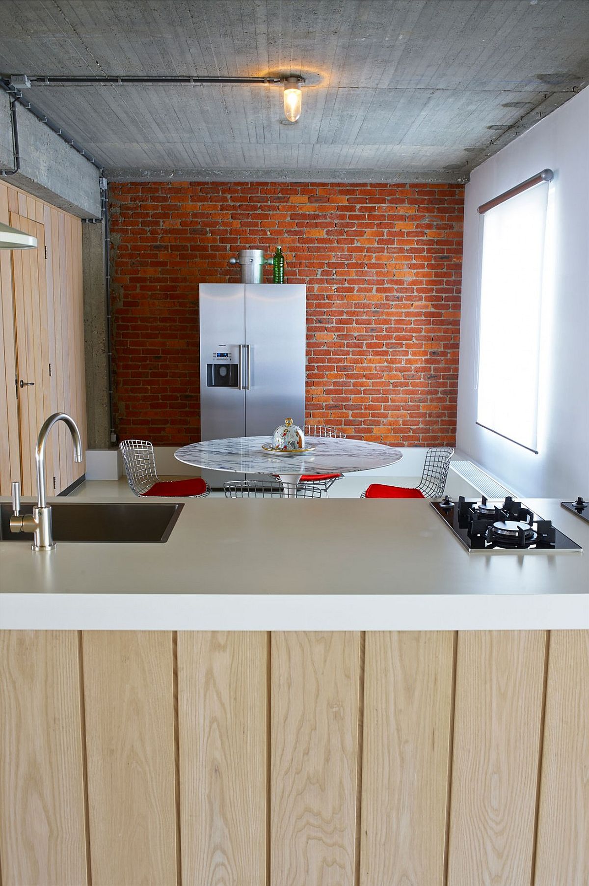 Brick wall in the backdrop of kitchen and dining room with Saarinen Tulip table
