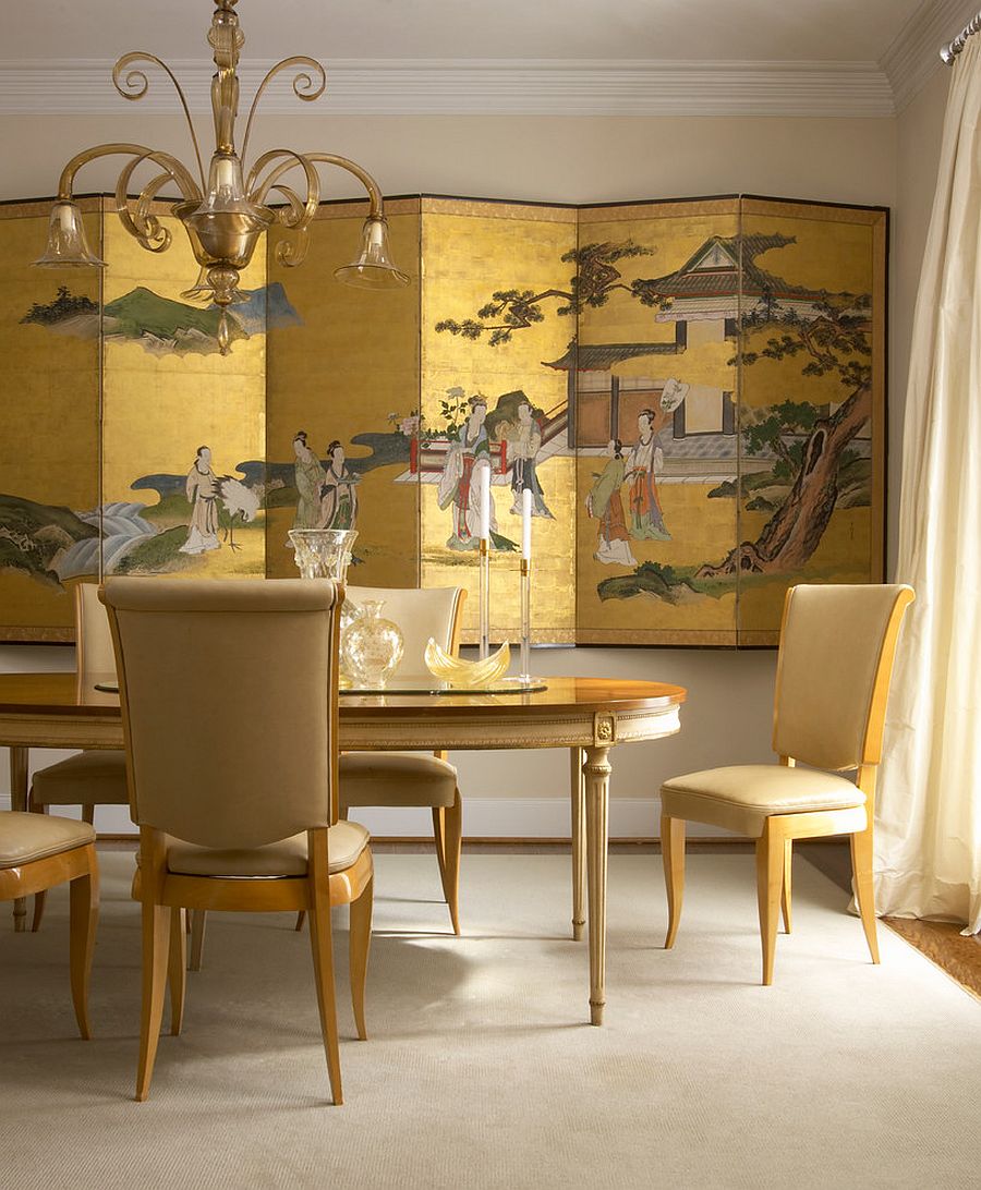 Chinese decorative screen in gold creates a dramatic backdrop for the dining room in gold