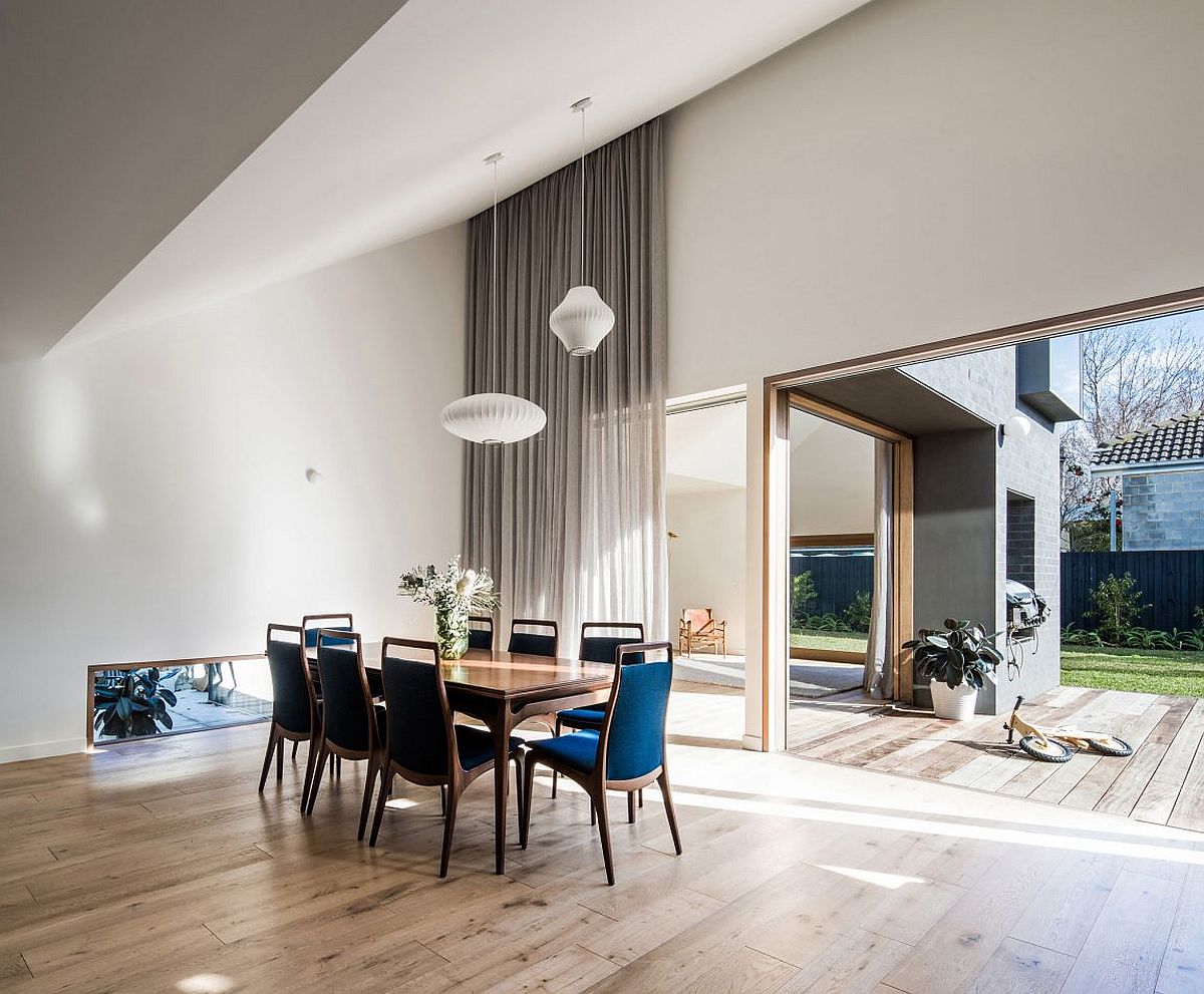 Dining space with Nelson pendants, bright blue chairs and an access to the yard