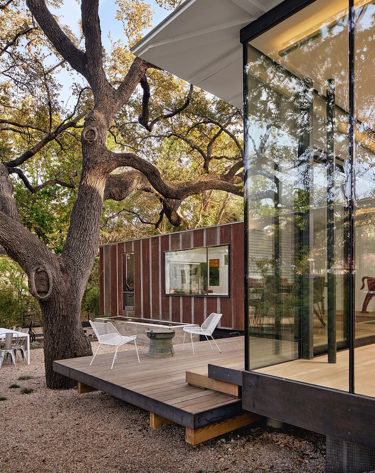 Glass walls connect the cottage with the outdoor terrace and green surroudings