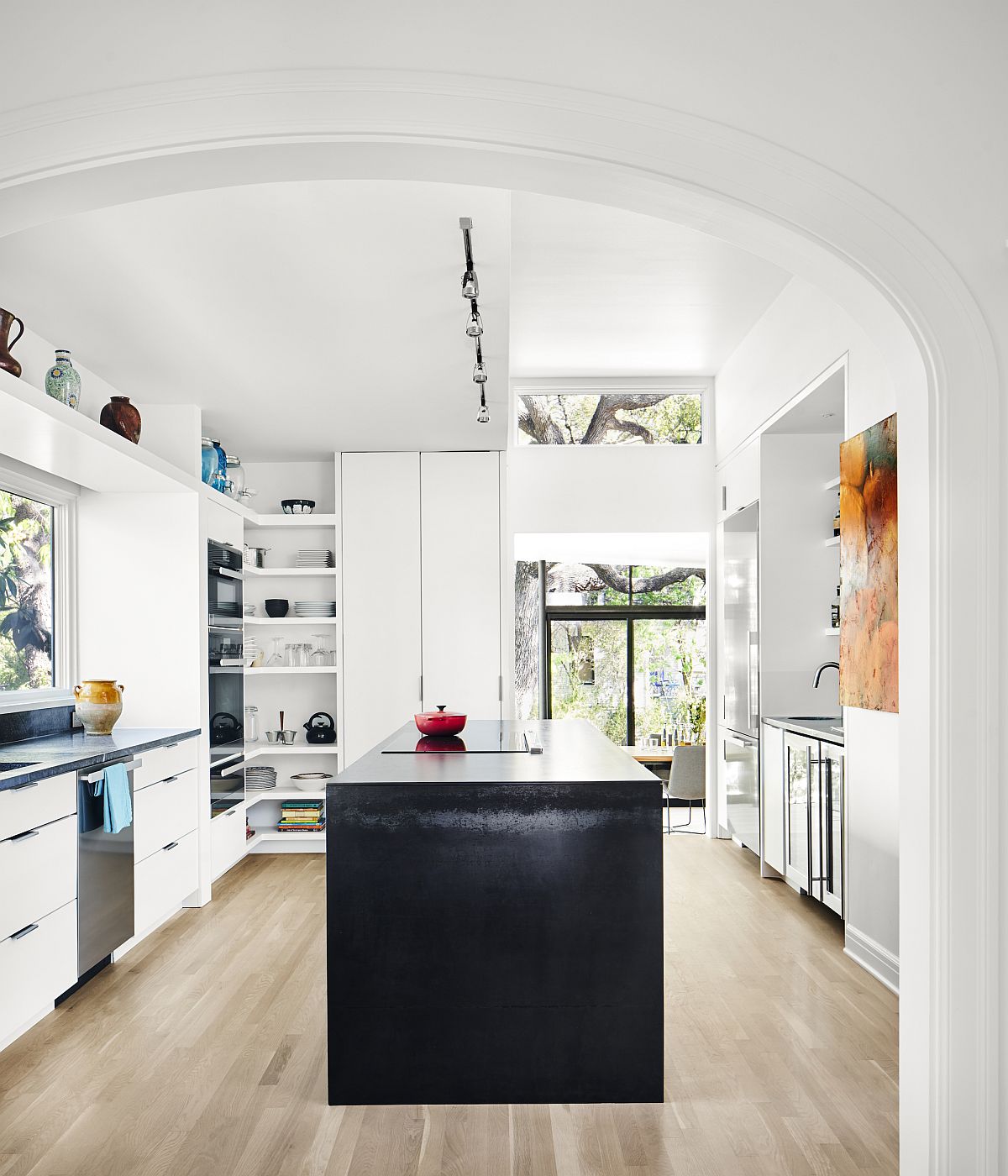 Kitchen in white with dark central island and colorful wall art