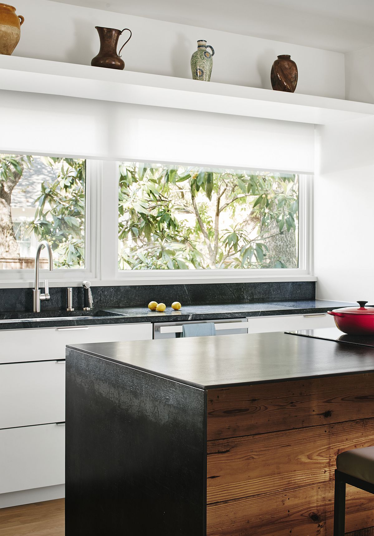 Large window connects the kitchen with the green yard outside