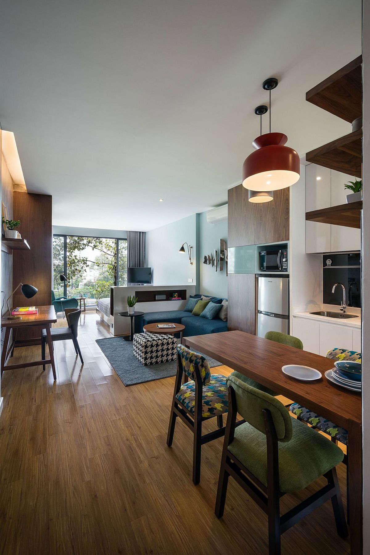 Open living area, kitchen and dining with a small sectional couch in blue and workdesk