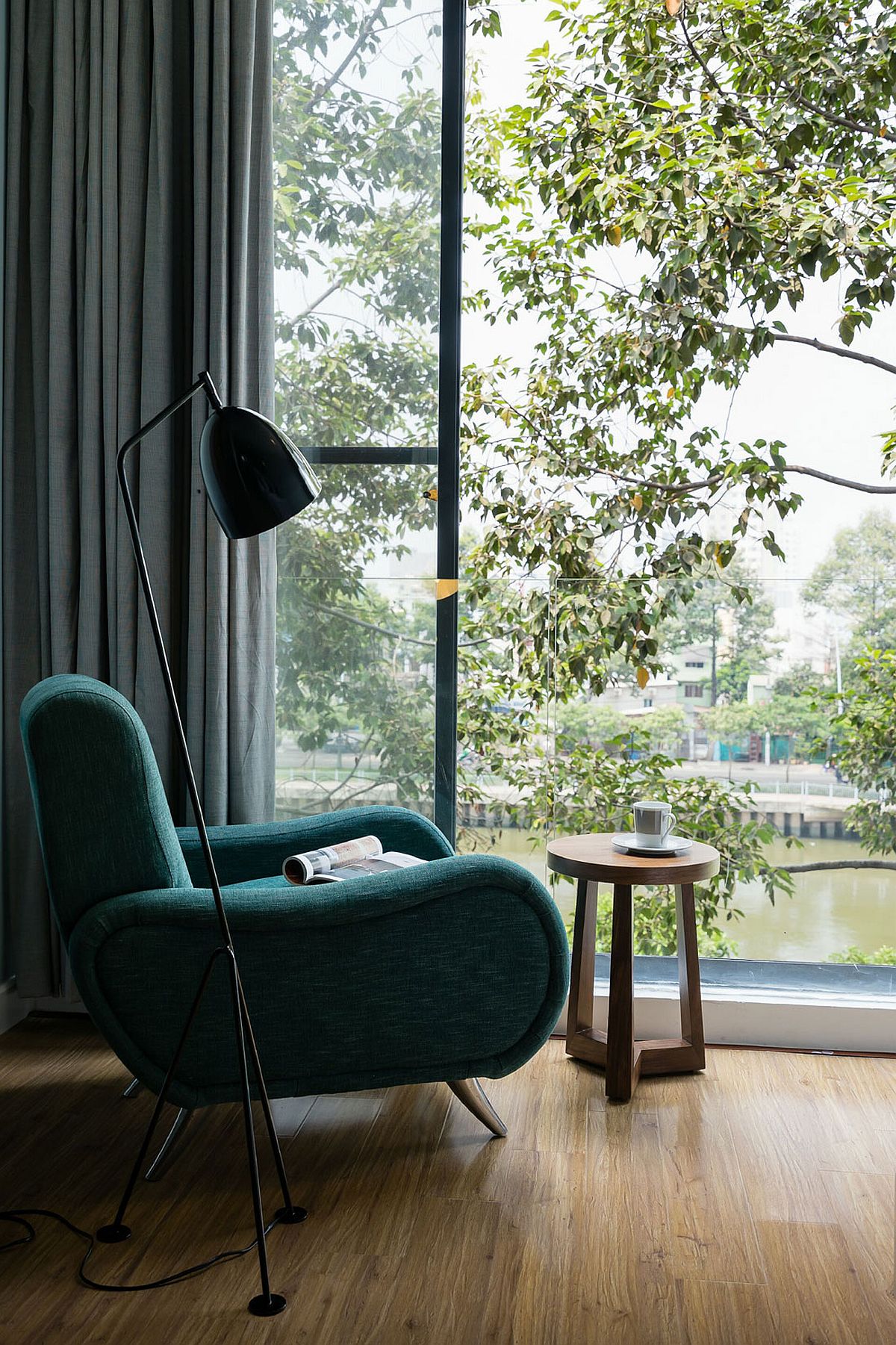 Simple reading nook with floor lamp that offers a view of the canal and green preserve around it