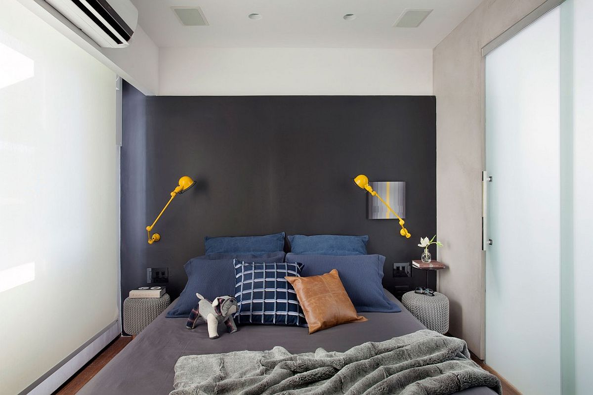 Small contemporary bedroom with gray accent wall and bright yellow sconce lighting