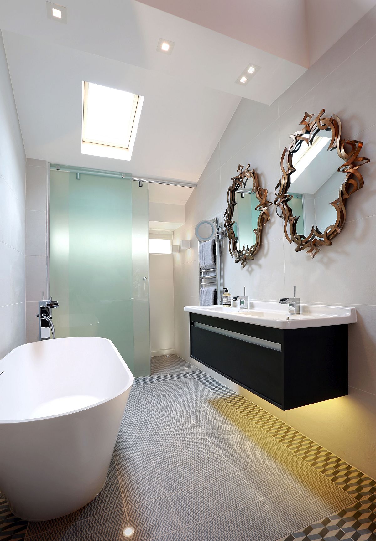 Space-savvy and exclusive master bathroom crafted by LLI Design with freestanding bathtub and striking mirrors above the floating vanity