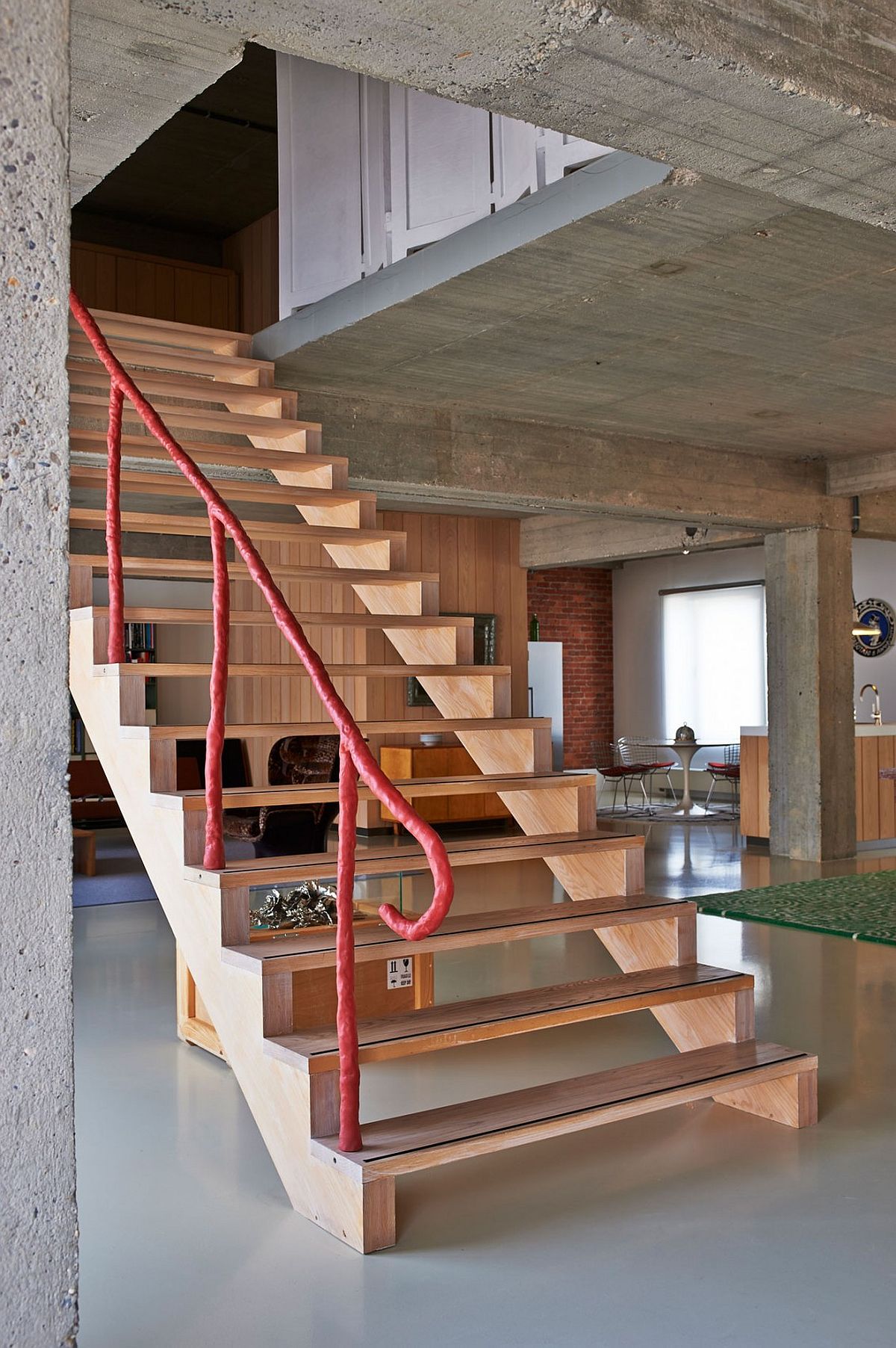 Striking wooden staircase with unqiue, colorful railing connects the two loft levels