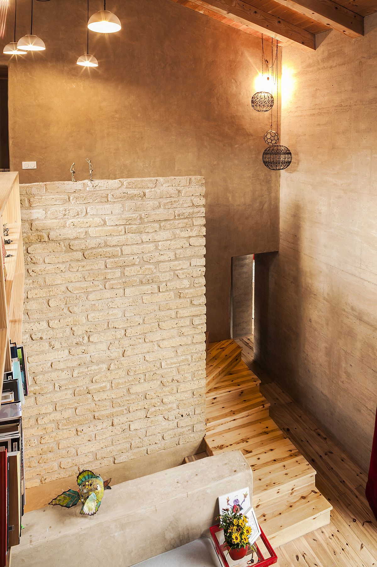 Brick and earthen walls give the double height living space a cool, inviting vibe