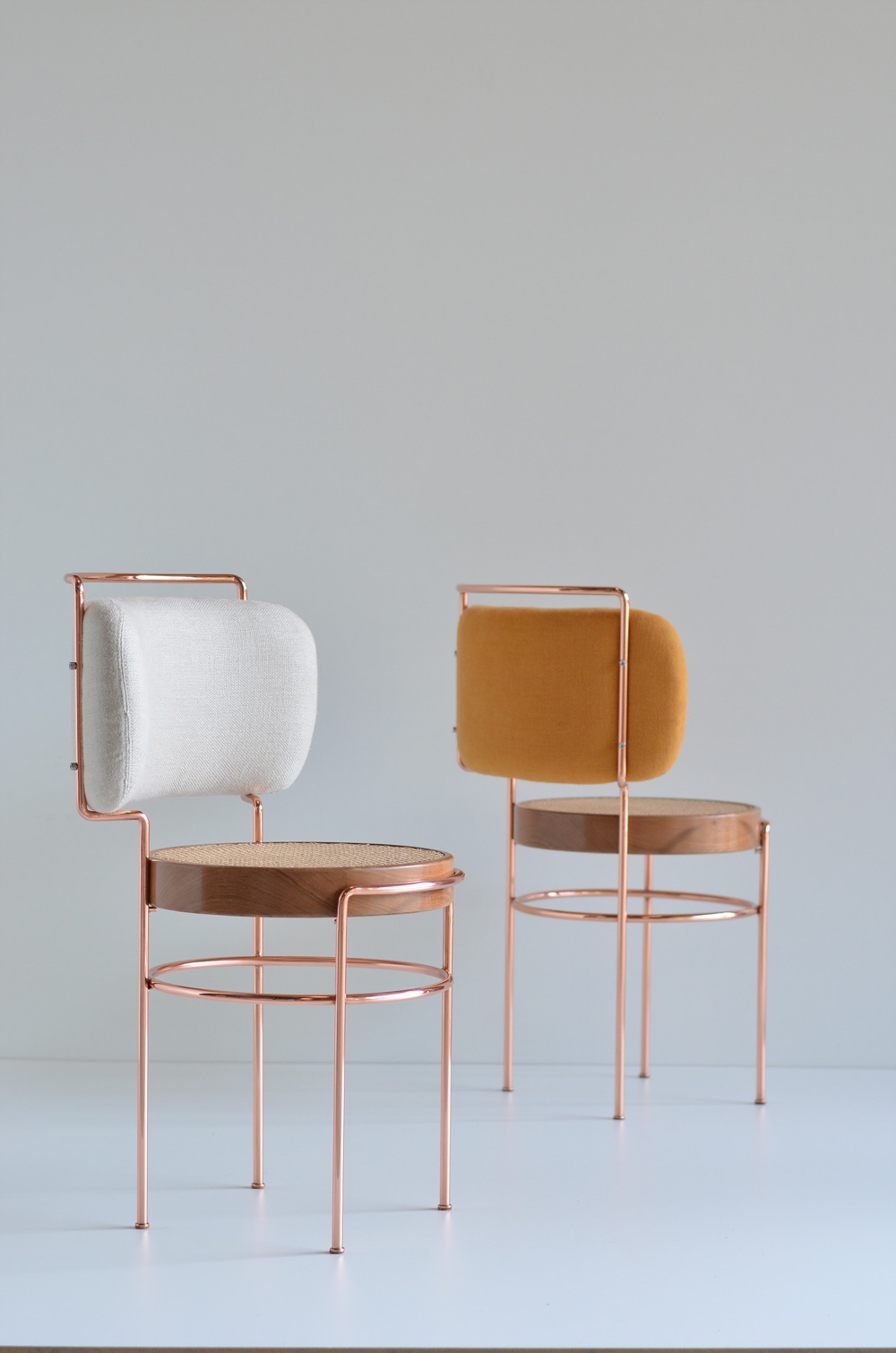 Cadeira IAIÁ by Gustavo Bittencourt draws inspiration from Brazilian modernism. Appearing feminine in shape, the chair is made using copper, solid wood, straw (for the seat) and fabric (for the backrest).