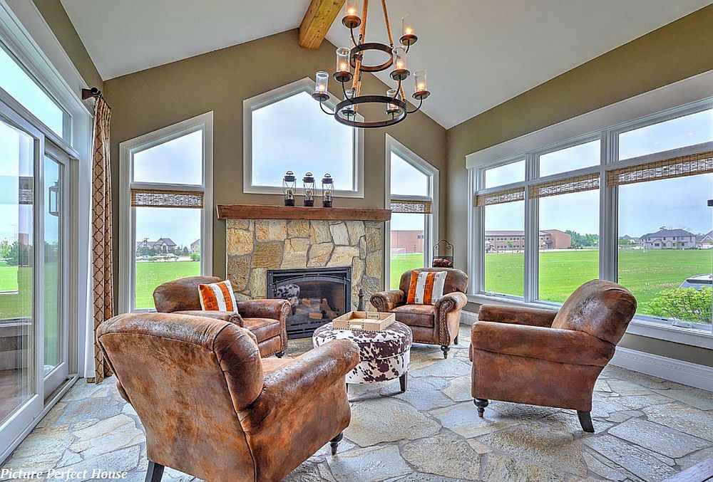 Large glass windows and doors and stone flooring shape the rustic sunroom