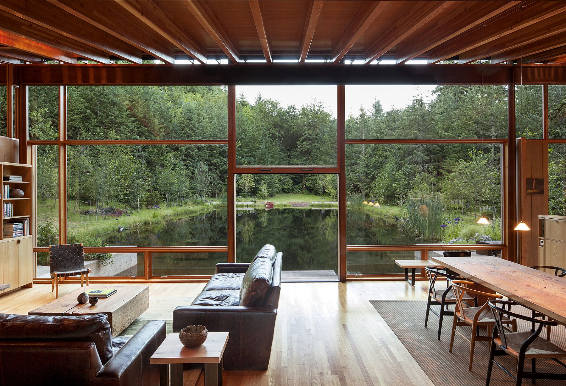 Living room flows into the overgrown landscape and the manmade pond