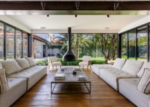 Living-room-with-glass-walls-and-fireplace-connecetd-with-the-garden-and-the-pool-outside-217x155