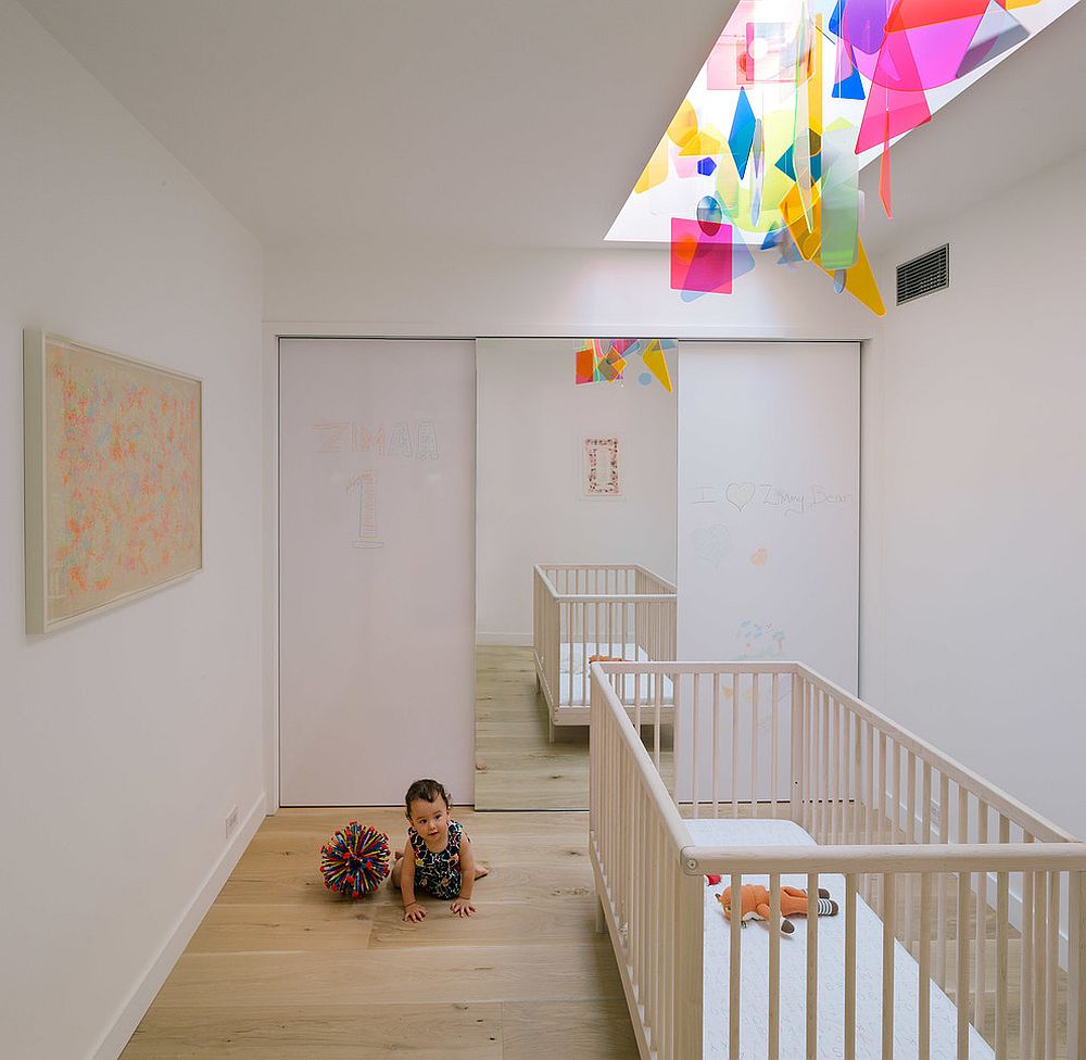 Contemporary nursery with colorful fixture above the crib