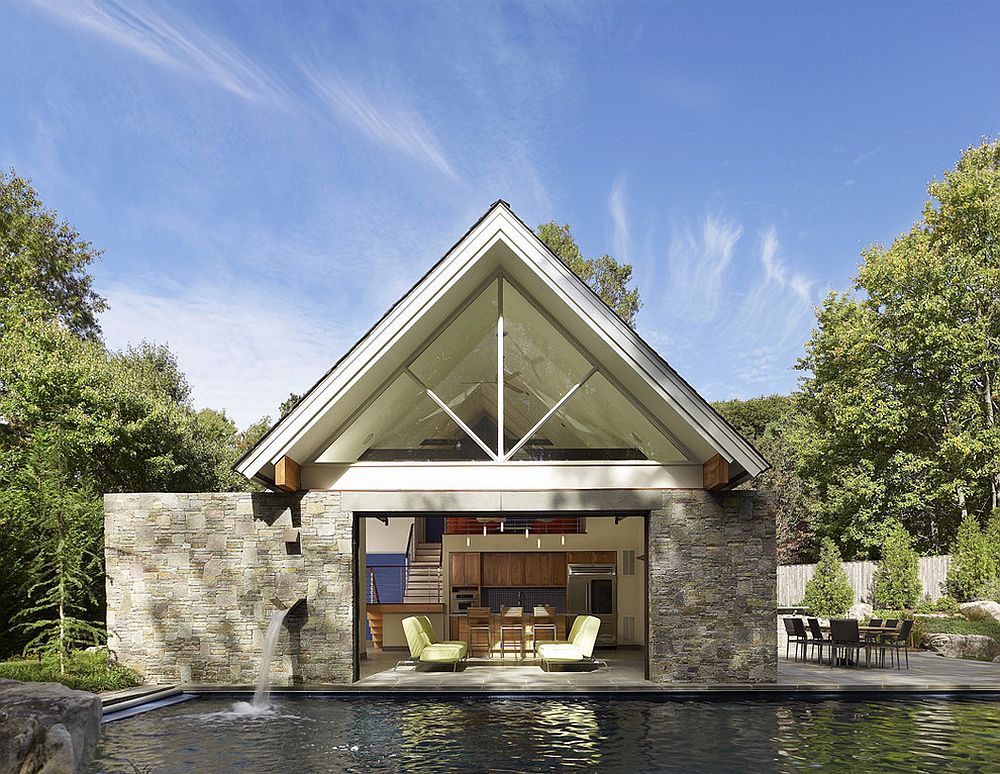 Contemporary pool house with glass garage door sits tight on the edge of the pool