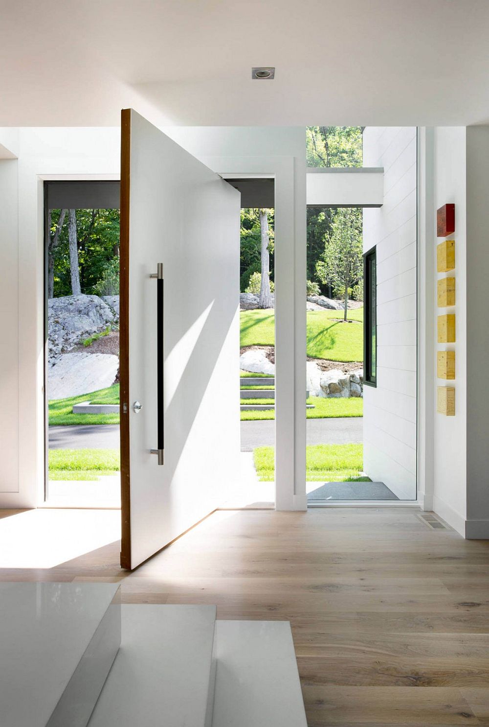 Pivoting door in white creates a dramatic entry at the Ledgewood Residence