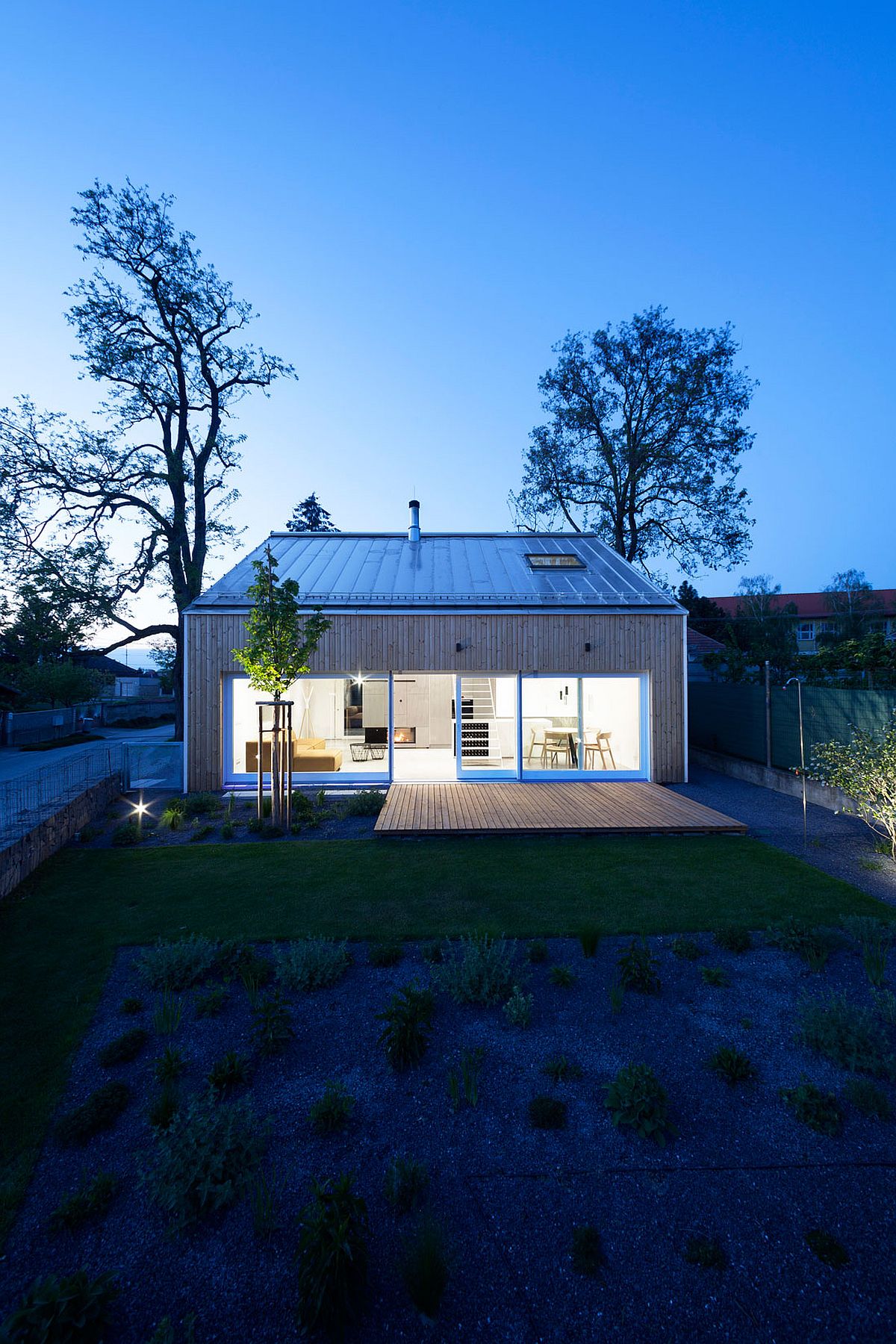 Sliding glass doors connect the interior with the deck and garden outside