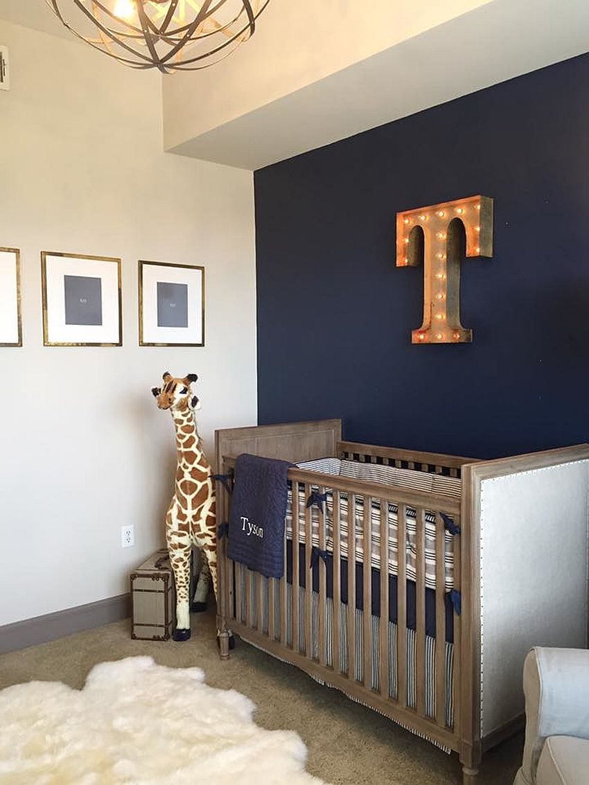 Stylish industrial nursery with dark blue accent wall and illuminated letter on the wall