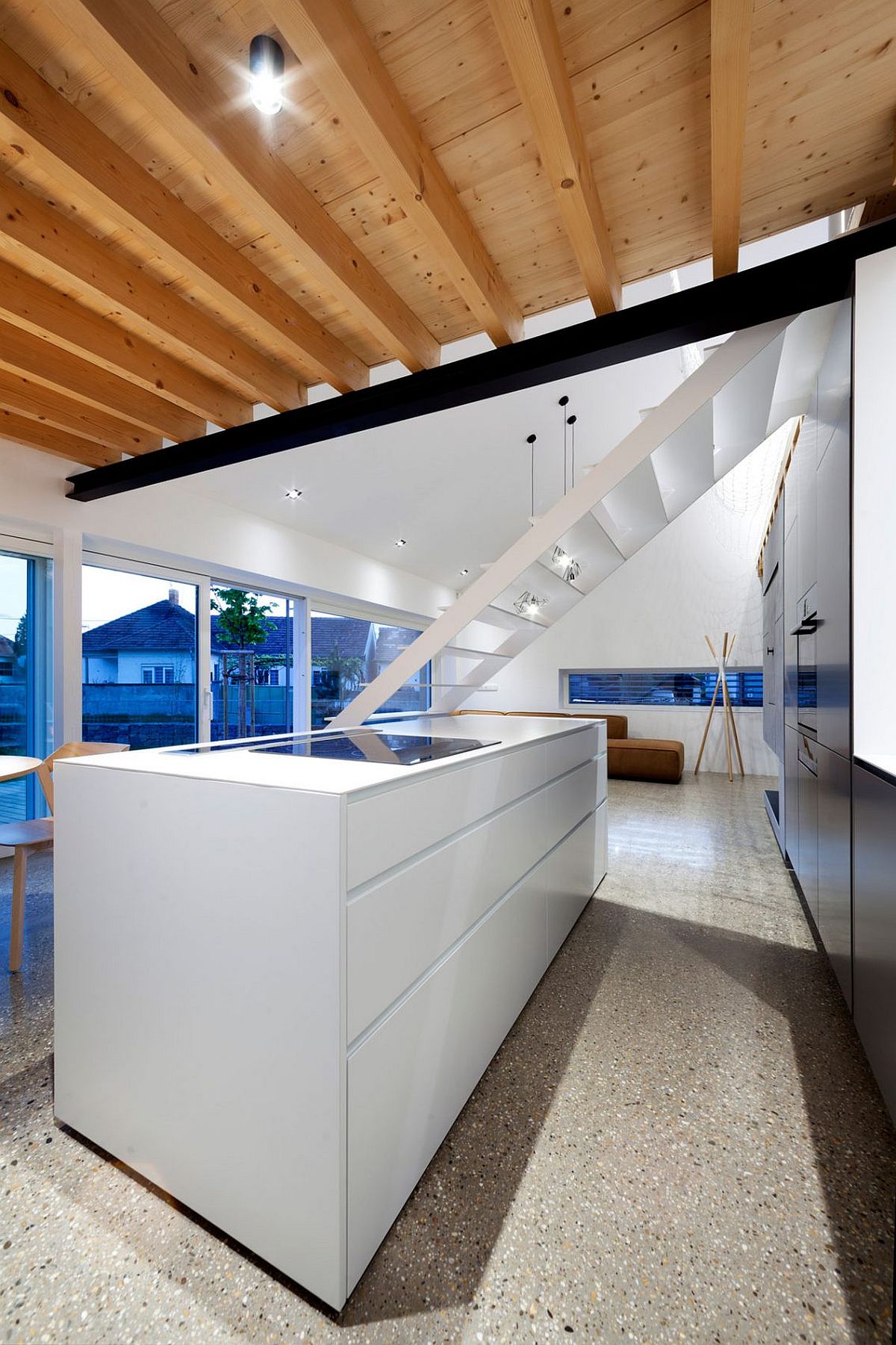 White kitchen island and dark kitchen wall in the open plan living area