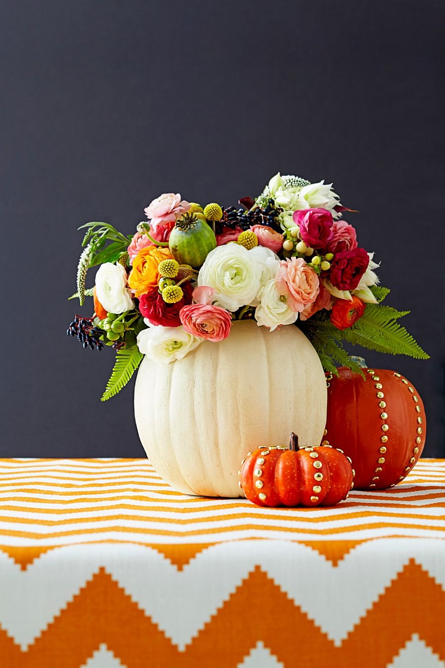 La colorida mezcla de flores y calabazas crea un impresionante centro de mesa