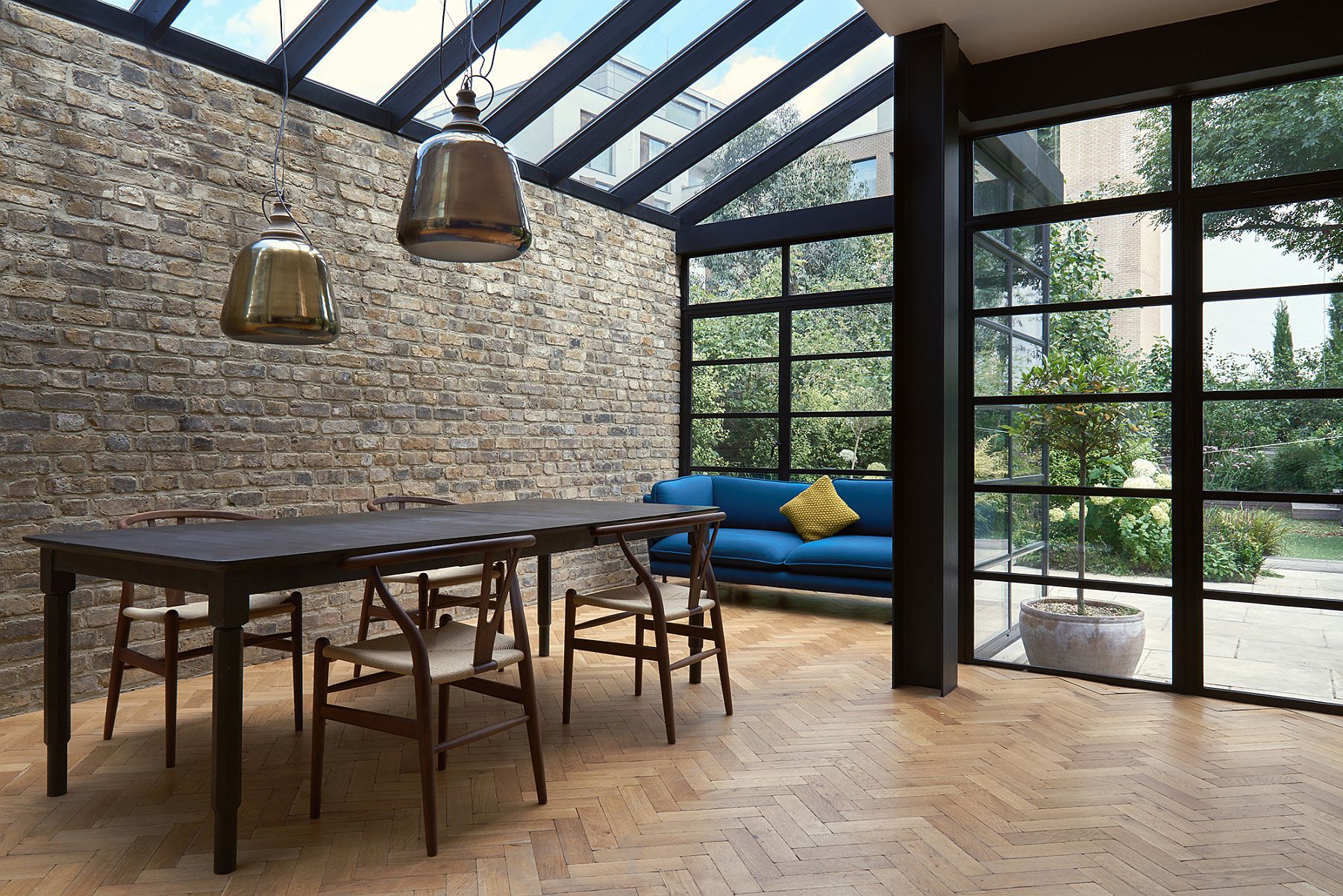 Contemporary dining area with cool pendant lights, brick wall and Crittal windows